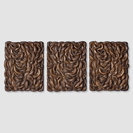 series of three rectangular wall mounted panels created from stacked interwoven black clay rings each mirroring the previous with gold glaze pooled in the ridges and crevices